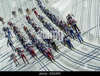 (dpa) - A group of skiers struggles uphill after the starting shot at the Nordic Skiing World Championship in cross-country skiing in Val di Fiemme, Italy, 22 February 2003. The competition is also called the skiathlon which involves the use of two different skiing techniques. For the first 10 kilometers athletes have to use the classical style and for the second 10 kilometers the  Stock Photo