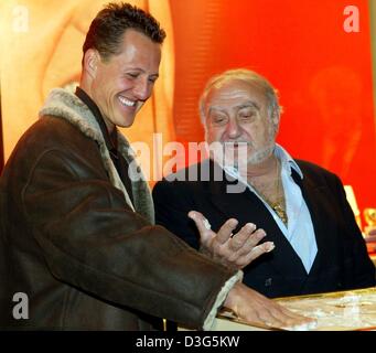 (dpa) - Swatch Group Chairman Nicolas G. Hayek (R) watches six-times formula 1 world champion Michael Schumacher (L) pressing his handprint in cement during the opening of the new OMEGA store in Munich, Germany, 26 November 2003. The luxury watch-maker Omega opened a new store in the posh Maximilianstrasse (Maximilian street). Stock Photo