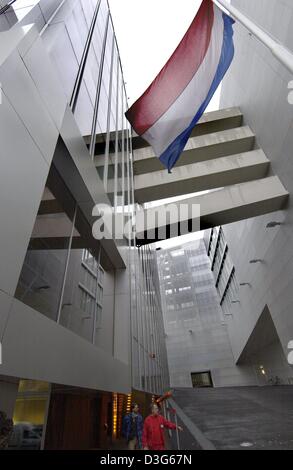 (dpa) - Two visitors (L, bottom) walk along the facade while the national flag of the Netherlands sways above the entrance of the new building of the Dutch embassy in Berlin, 17 November 2003. The dutch architect Rem Koolhaas, won with his design this year's Berlin Prize for Architecture. Stock Photo