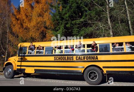 (dpa) - School kids are waving from the original bright yellow American school bus during a cruise in Erlabrunn, Germany, 11 November 2003. The unusual business idea offers the bus for hire for school trips, weddings or for groups. The two-man company is called 'Schoolbus California'. The bus, which had until recently been in service in Philadelphia, had to undergo many changes to  Stock Photo