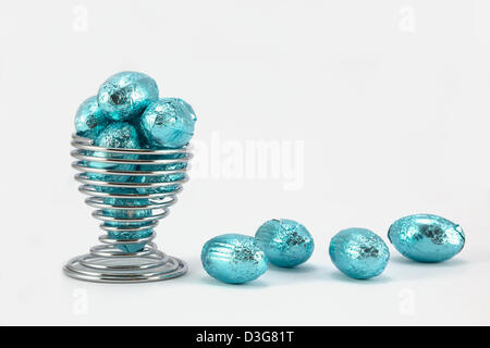 Bright blue small foil wrapped easter eggs in a wire eggcup. Stock Photo