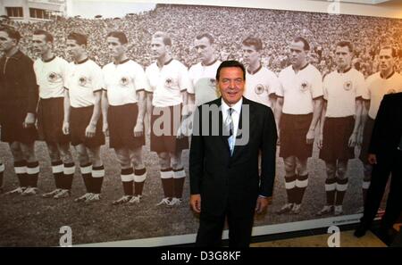 (dpa) - German Chancellor Gerhard Schroeder stands in front of a photo of the German soccer team of 1954, ahead of the premiere of the movie 'The Miracle of Bern' ('Das Wunder von Bern') in a cinema in Essen, Germany, 15 October 2003. The film, set in a war-torn Germany, tells the story of the first German World Cup victory of 1954 in Bern, Switzerland, from the point of view of an Stock Photo