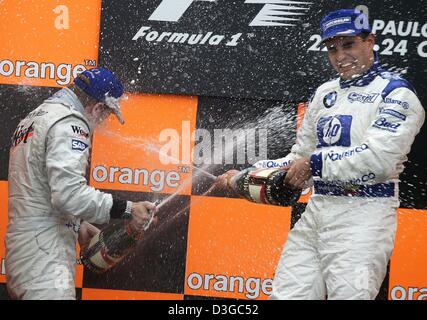 (dpa) - Colombian Formula One driver Juan Pablo Montoya (R) of BMW-Williams celebrates on the podium with second placed Finish Kimi Raeikkoenen (L) of McLaren Mercedes after winning the Brazilian Formula One Grand Prix at the Interlagos circuit in Sao Paulo, Brazil, Sunday 24 October 2004. Stock Photo