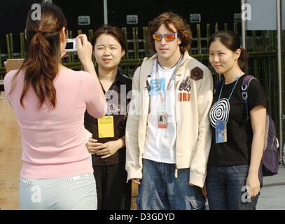 (dpa) - Spanish Formula 1 driver Fernando Alonso (2nd from R) poses for a photograph with a couple of Chinese fans at the futuristic looking pit area of the new Shanghai International Circuit in Shanghai, China, 22 September 2004. The Chinese Grand Prix, the first ever Formula One race on Chinese soil, will take place on Sunday, 26 September 2004. Stock Photo