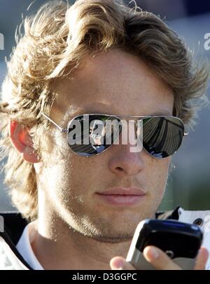 (dpa) - British formula one pilot Jenson Button (BAR Honda) looks on the display of his mobile phone on the formula one racing track in Spa-Francorchamps, Belgium, Friday, 27 August 2004. The Belgian Grand Prix will be held in Spa on Sunday, 29 August 2004. Stock Photo