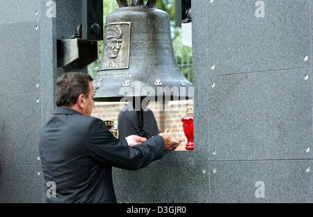 (dpa) - German Chancellor Gerhard Schroeder places a lit candle underneath a bell at the memorial wall which commemorates the resistance fighters and people killed in the Warsaw Uprising, in Warsaw, Poland, 01 August 2004. Schroeder was among the international guests who participated in the celebrations commemorating the 60th anniversary of the Warsaw Uprising. Stock Photo