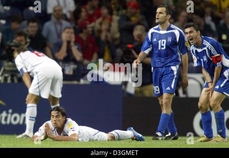 (dpa) - Greek midfielder Theodoros Zagorakis (R) stands next to his teammate Michalis Kapsis (2nd from R) shouts comments across the pitch to his teammates, while Czech forward Milan Baros (bottom) lies on the pitch next to Czech player Karel Poborsky (L), regretting his missed chance to score a goal during the Soccer Euro 2004 semifinal opposing Greece and the Czech Republic in Po Stock Photo