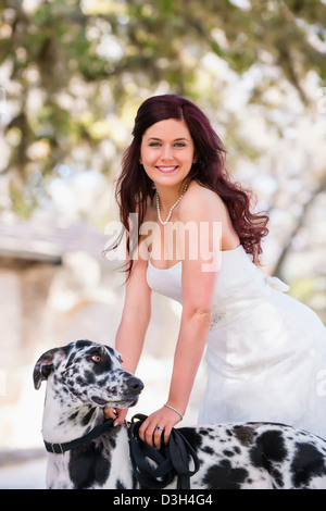 Smiling bride in wedding dress with black and white Great Dane dog Stock Photo