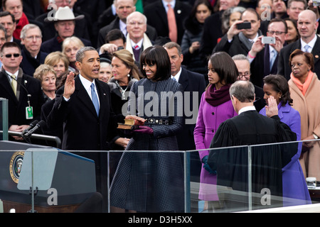 US Supreme Court Chief Justice John Roberts administers the oath of office to President Barack Obama during the inaugural swearing-in ceremony at the US Capitol January 21, 2013 in Washington, DC. First Lady Michelle Obama holds a Bible that belonged to Dr. Martin Luther King Jr., and the Lincoln Bible, which was used at President Obama’s 2009 inaugural ceremony. Daughters Malia and Sasha stand with their parents. Stock Photo