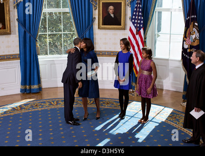 US President Barack Obama and First Lady Michelle Obama embrace following the official swearing-in ceremony in the Blue Room of the White House on Inauguration Day January 20, 2013 in Washington, DC. Standing, from left, are daughters Sasha and Malia and Supreme Court Chief Justice John G. Roberts, Jr. Stock Photo