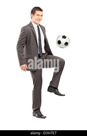 Full length portrait of a young handsome businessman kicking a football isolated on white background Stock Photo