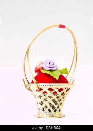 A miniature metalic wicker decorated by roses on a red velvet isolated on white background Stock Photo
