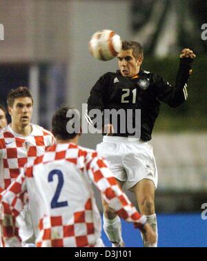 (dpa) The German defender Philipp Lahm (right) jumps for a header in front of his Croatian opponents Darijo Srna (Nr. 2) and Ivan Klasnic (left, background). Lahm gave his debut in the German national soccer team. The German and Croation national soccer teams meet in a friendly soccer match on 18 February 2004 in Split, Croatia. The German team beat Croatia  2:1: in their first mat Stock Photo