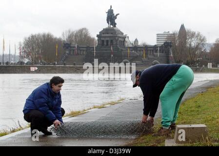 (dpa) - Two employes of the camping site which is situated on the river bank opposite the 'Deutsches Eck' (German corner), which marks the confluent of the Rivers Rhine and Mosel in Koblenz, Germany, 13 January 2003. The employees dismantled the fence to prevent it from flood damages. Continious rainfall causes rising water levels in several German rivers and floodings are expected Stock Photo
