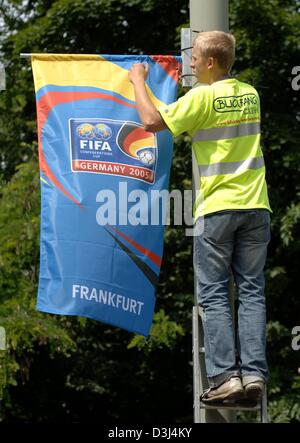 (dpa) - Technician Nils Reuter puts up small flags with the logo of the FIFA Confederations Cup onto lamp posts in Frankfurt, Germany, Wednesday 9th June 2005. More than 200 of these addvertisements will be placed in the area of the new soccer arena. Serving as well as a preparation for the Soccer World Cup 2006 in Germany, the Confederations Cup will take place in four German citi Stock Photo