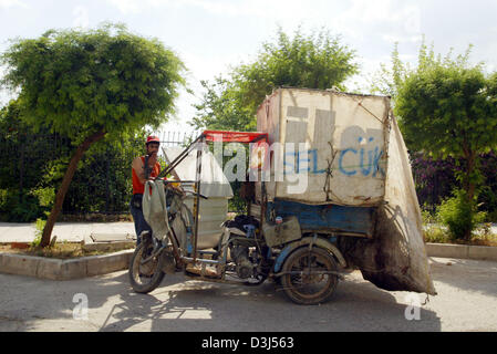 (dpa) - The picture shows a man smoking a cigarette beneath his vehicle in Antaly, Turkey, 14 May 2005. He sells plastic and paper waste to a recycling company. Stock Photo
