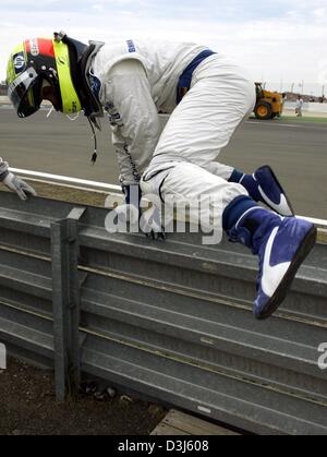 (dpa) - German formula one pilot Ralf Schumacher (BMW-Williams) climbs over the crash barrier after his accident during the European Grand Prix at the Nuerburgring race track in Germany, 30 May 2004. Stock Photo