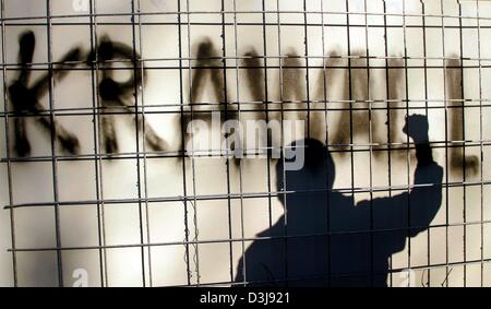 (dpa) - The silhouette of a young man gesturing with his fist appears at a wall with the writing 'Krawall' (riot) on it in Berlin, 14 April 2004. Berlin's police force is preparing for the annual riots which usually take place between 30 April and 1 May 2004. Around 10,000 officers from throughout Germany will be deployed in Berlin for that particular weekend. Stock Photo