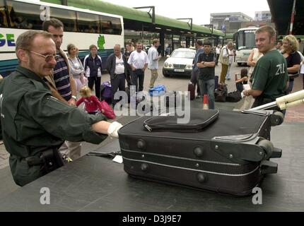 (dpa) - A customs officer places a piece of luggage on a mobile x-ray scanner while the passangers wait to continue their journey during a control check long-distance coaches in Hanover, Germany, 18 August 2003. German police and customs officers conducted joint operation to check on overland busses in an attempt to tackle smuggling, careless safety violations and technical shortco Stock Photo