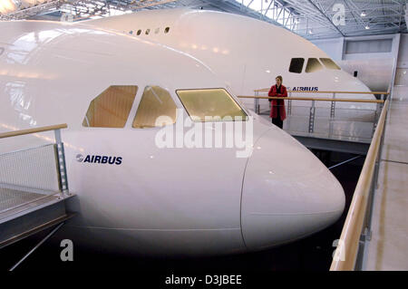 (dpa) - A woman in a red coat looks at a full size model (mock up) of the Airbus A340 aircraft (front) at Airbus headquarters in Toulouse, France, 20 April 2005. In the background is a mock up of the new A380. The A380 will be the world's biggest civil aircraft. First test flights are scheduled for the beginning of May 2005.