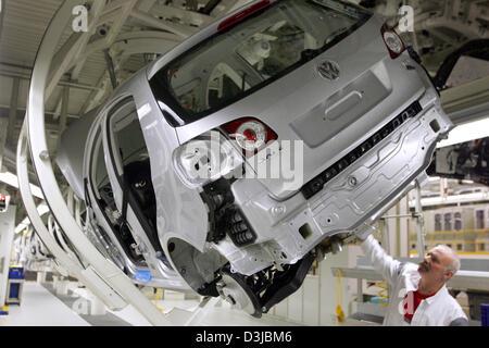 (dpa) - An employee mounts a car part to the bottom of a VW Golf Plus at the Volkswagen assembly plant in Wolfsburg, Germany, 22 Febuary 2005. VW employs 103,800 workers in Germany of which around 50,200 work at the main production plant in Wolfsburg.