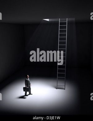 A lonely man standing in a spot of light coming from an opening in the ceiling Stock Photo