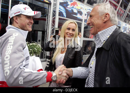 (dpa) - Austrian billionaire Dietrich Mateschitz (R), owner of Red Bull Formula One racing team, laughs greet German Formula One driver Ralf Schumacher (L) of Toyota and his wife Cora Schumacher with a handshake in the paddock at the Formula One racetrack in Imola, Italy, 23 April 2005. Stock Photo