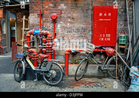 Bikes and red water pipes in an alley of Tianzifang, a renovated area in the French Concession near Taikang Lu, Shanghai - China Stock Photo