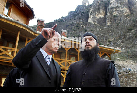 (dpa) - German Defence Minister Peter Struck (L) gestures as he speaks with a monk during his visit to the archangel monastery in Prizren, Serbia and Montenegro, 22 March 2005. The monastery was destroyed during a civil unrest a year ago. Struck paied a visit to the 3200 German KFOR troops at the Prizren military camp during his two-day trip through the Balkans. Stock Photo