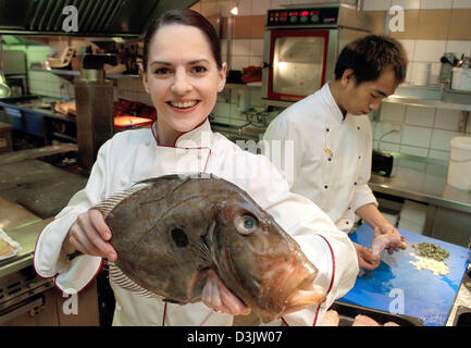 (dpa) -  Sybille Milde smiles as she holds a St Peters fish in her hands at the Hessler restaurant in Maintal, Germany, 23 December 2004. The 27-year-old chef is now in charge of the one-star-restaurant after former owner passed away.  The famous gourmets Gault Millau and Michelin left the gourmet star with the restaurant. Stock Photo
