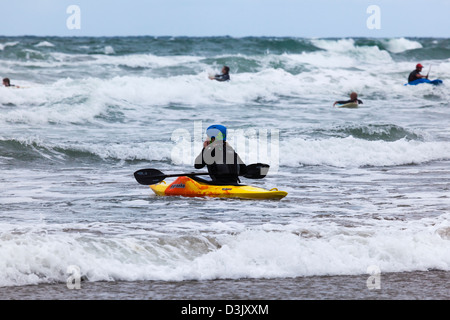 A woman waits in the breaking waves at Black Rock Beach, Widemouth Bay, nr Bude, Cornwall, UK Stock Photo