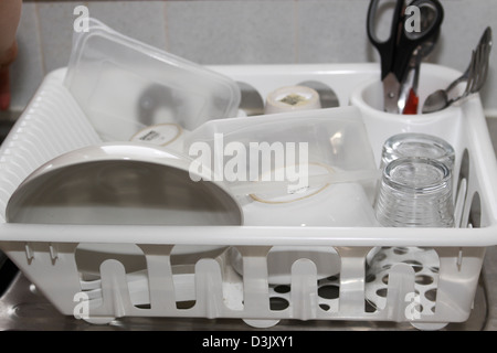 Dishes in plastic drying rack on draining board Stock Photo