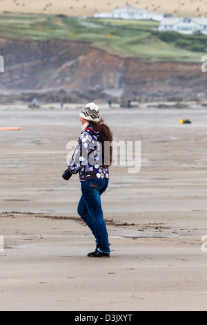 A woman photographer takes surfing pictures at Black Rock beach, Widemouth Bay, nr Bude, Cornwall Stock Photo