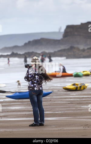 A woman photographer takes surfing pictures at Black Rock beach, Widemouth Bay, nr Bude, Cornwall Stock Photo