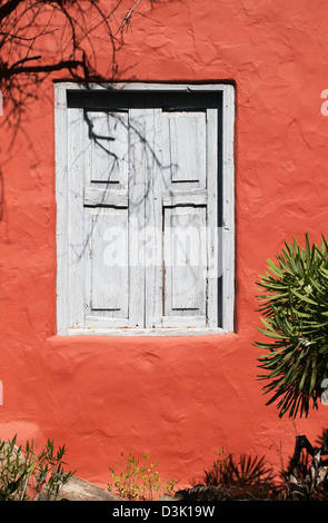 Faded blue grey wooden window shutters against an orange red wall Arteara, San Bartolomé de Tirajana Stock Photo