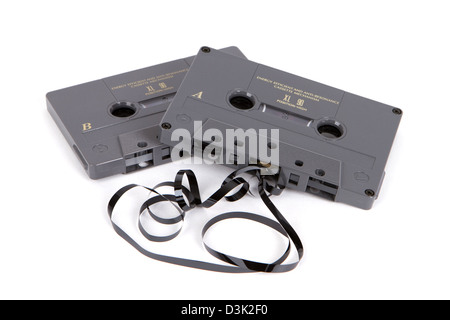 Obsolete magnetic audio cassette tapes partially unwound on a white background. Stock Photo