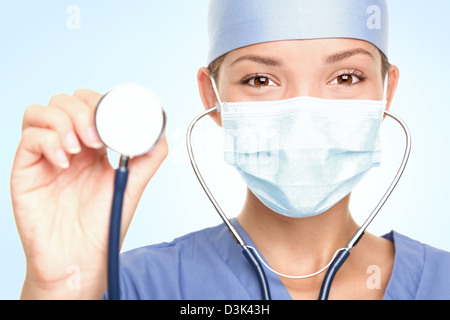 Portrait of Asian / Caucasian young female doctor / surgeon wearing surgeon mask showing stethoscope Stock Photo