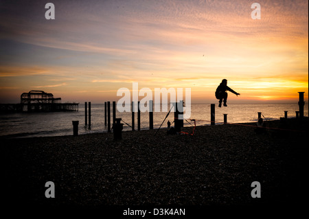 A man jumps high from his tightrope  on Brighton Beach by the West Pier Stock Photo