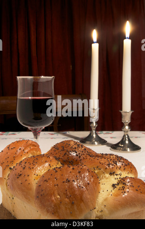 Shabbat includes Challah, or egg bread shot up close,glass of wine,two candles lit, two candle sticks. Stock Photo