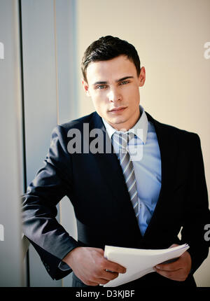 Serious young businessman with papers looking at camera Stock Photo