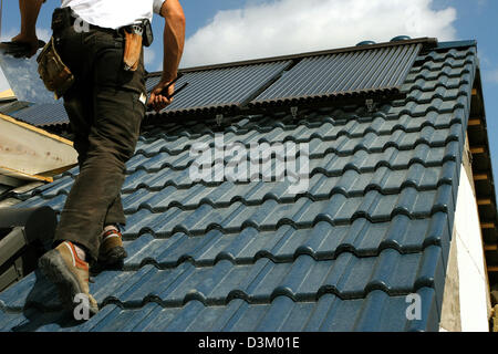 (dpa) - The picture shows a roofer on a roof top with solar panels in Kelsterbach, Germany, 24 August 2005. Photo: Heiko Wolfraum Stock Photo