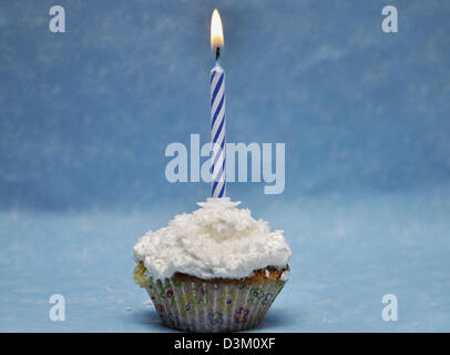 Vanilla cupcake with lit candle on top Stock Photo