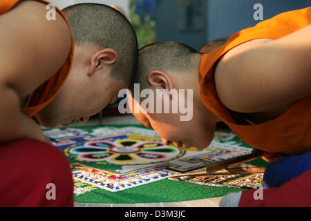 (dpa) - Tibetan nuns of the cloister Khachoe Ghakyil in Kathmandu, Nepal craft a sand mandala of Chenresig in the Overseas museum in Bremen, Germany, Friday 4 November 2005. To craft the mandala they sprinkle coloured sand on the picture with small tubes. The coloured art work made of sand following the Chensrig motive will be fixed and enrich the new constructed Asia department of Stock Photo