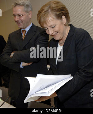 (dpa) - Designated German Federal Chancellor and CDU Chairwoman Angela Merkel skims through the coalition agreement, which the CDU, CSU and SPD negotiated as basis for their grand coalition, while her colleague Norbert Roettgen stands next to her prior to a CDU/CSU caucus at the Reichstag building in Berlin, Germany, 13 November 2005. The Union faction met to debate the coalition a Stock Photo