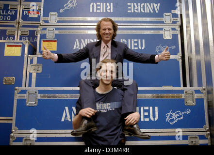 (dpa) - Dutch star violinist Andre Rieu (top) and his son Pierre (24) pose in front of large containers featuring Andre Rieu's name at his warehouse in Maastricht, the Netherlands, 02 November 2005. The 56-year-old musician is about to start the first part of his tour through Canada and the USA, where he will perform at 13 mayor cities. The complete equipment of his crew, which num Stock Photo