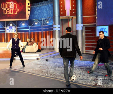 (dpa) - British pop star Robbie Williams (R) wears red socks while playing soccer with German national soccer player Kevin Kuranyi (C) and host Thomas Gottschalk (L) during the German TV show 'Wetten, dass...?' ('Bet that...?') in Duesseldorf, Germany, 10 December 2005. Numerous international celebrities and German artists were among the guests of Europe's most successful TV show.  Stock Photo