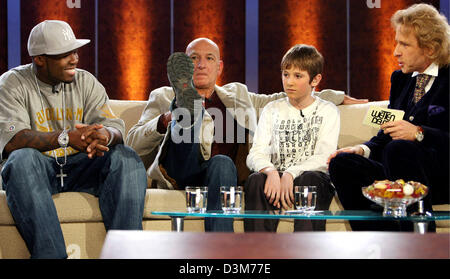 (dpa) - British actor Sir Ben Kingsley (2nd from L) shows his shoe while sitting next to his little film partner Barney Clark (both perform in 'Oliver Twist'), US rapper '50 Cent' (L) and German TV host Thomas Gottschalk (R) during the German TV show 'Wetten, dass...?' ('Bet that...?') in Duesseldorf, Germany, 10 December 2005. Numerous international celebrities and German artists  Stock Photo