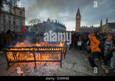 Protesting students dancing round a park bench which has been set on fire in Parliament Square, with the Big Ben tower and Parliament behind, Day X3 Student Demonstration, London, England Stock Photo