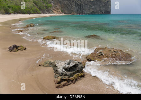 Waves breaking over volcanic rocks on the sandy beach at Rendezvous Bay, Montserrat Stock Photo