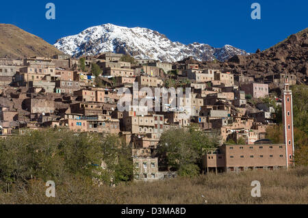 Steeply terraced village of Aremd with snow-capped mountain behind, near Imlil, Morocco Stock Photo